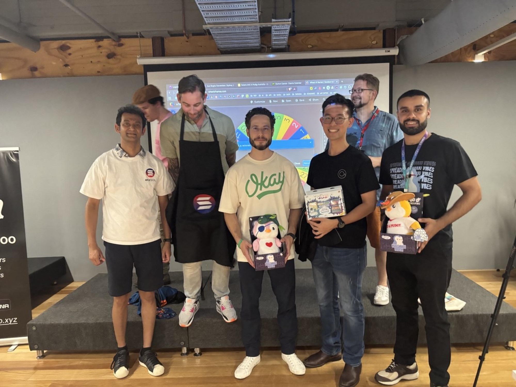 Winners holding plush prizes and merch on stage