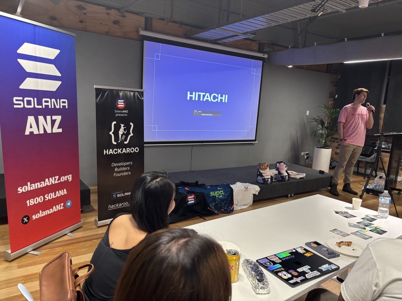 Speaker on stage with HITACHI slide